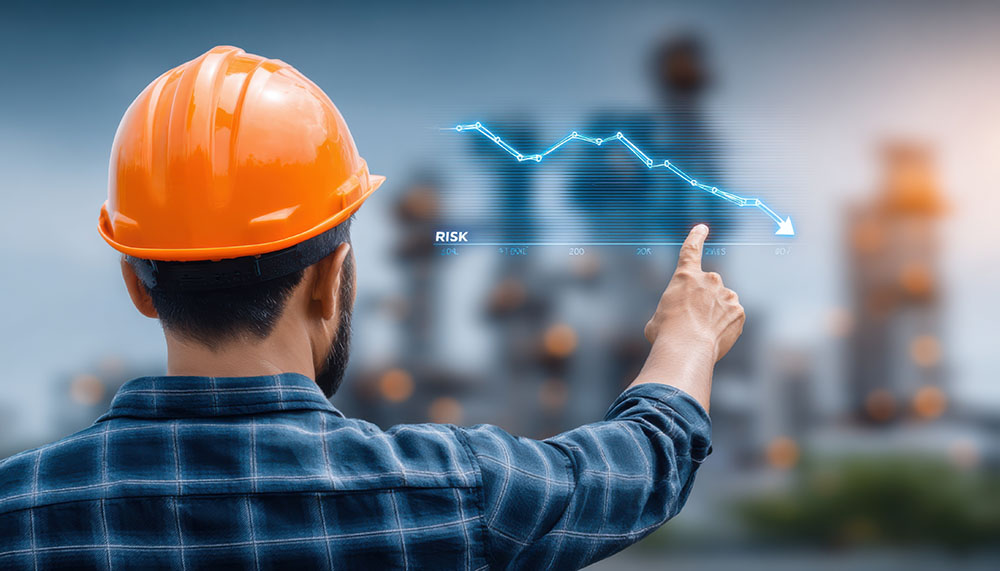 산업 시설을 배경으로 설비종합효율의 성능 손실을 나타내는 하락 추세 그래프를 가리키는 안전모를 쓴 작업자